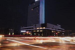 Un edificio moderno con una cuadrícula de luces en su fachada, una banda vertical de luces destacada y una banda horizontal en la base.