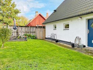 A residential property with a well-maintained lawn, a wooden fence, and a house with a blue door. - 6 Person Holiday Home in Tomelilla (Tomelilla)