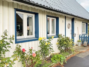 A row of white and blue-framed windows with a metal roof, surrounded by various plants and a blue picket fence. - 6 Person Holiday Home in Tomelilla (Tomelilla)
