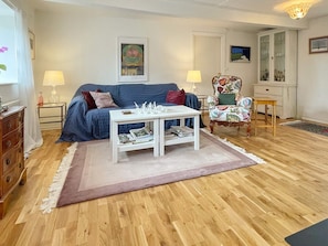 A living room with a blue sofa, a white coffee table, a patterned armchair, and a wooden cabinet. - 6 Person Holiday Home in Tomelilla (Tomelilla)
