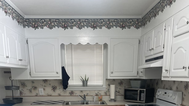 A kitchen with white cabinets, a microwave, a stove, and a sink. - Papa & Mema’s Farmhouse (Hazlehurst)
