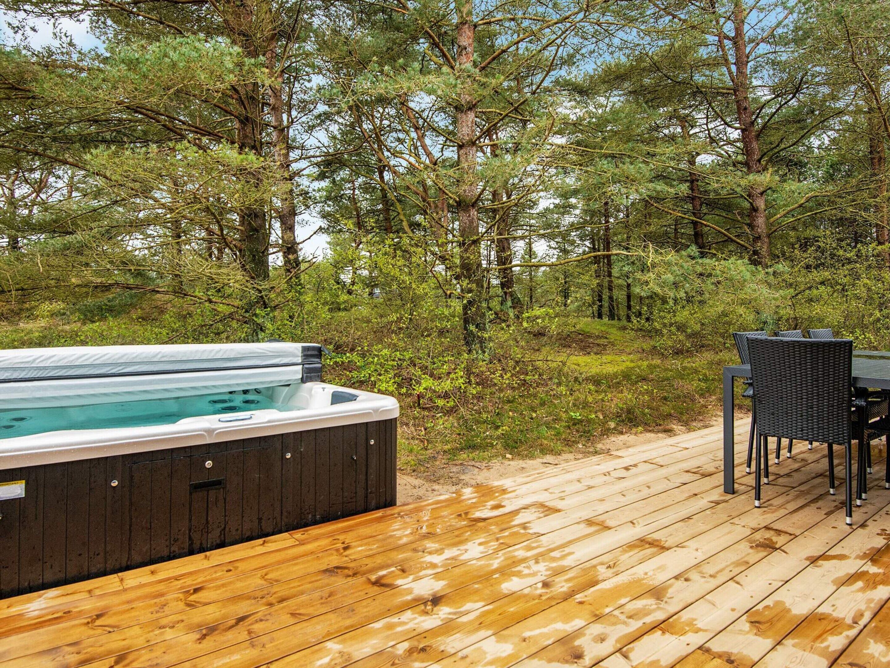 A hot tub on a wooden deck surrounded by trees.