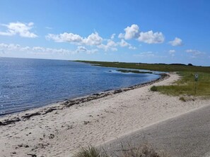 Une route côtière bordée d’une plage de sable et surplombant un ciel bleu azur.