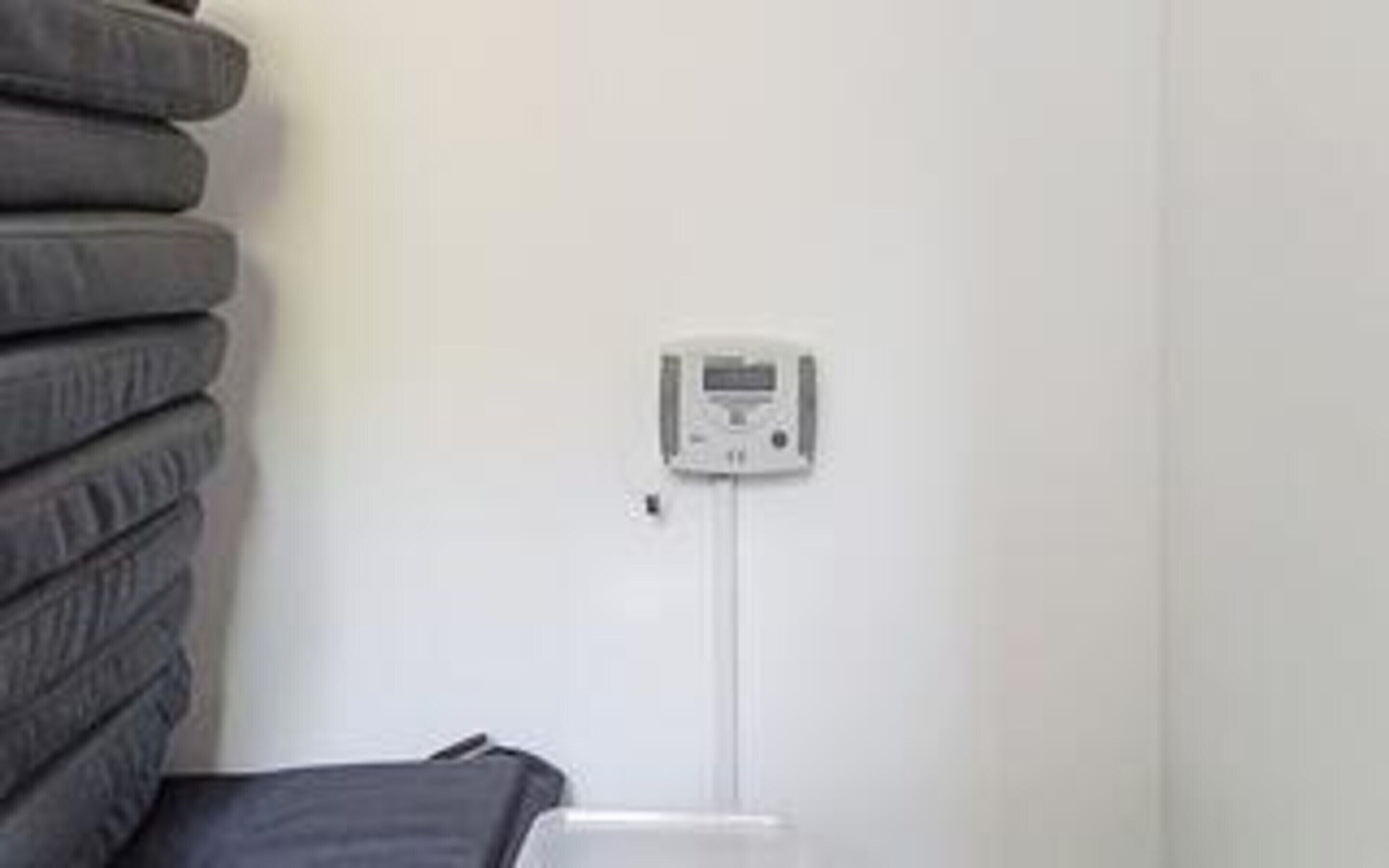A white wall with a thermostat and a power outlet.