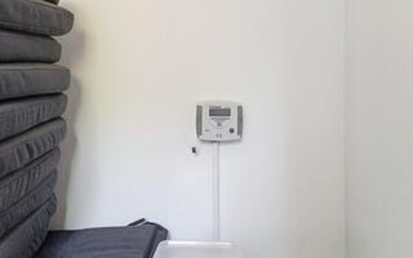A white wall with a thermostat and a power outlet.