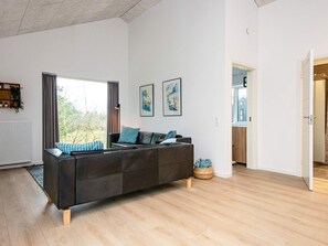 Un salon moderne avec un canapé, une fenêtre et une porte donnant sur une autre pièce.