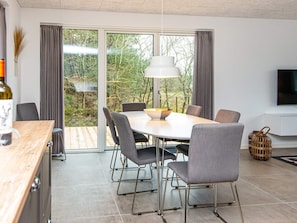 Un comedor moderno con una mesa grande, sillas tapizadas de color gris y una lámpara colgante.