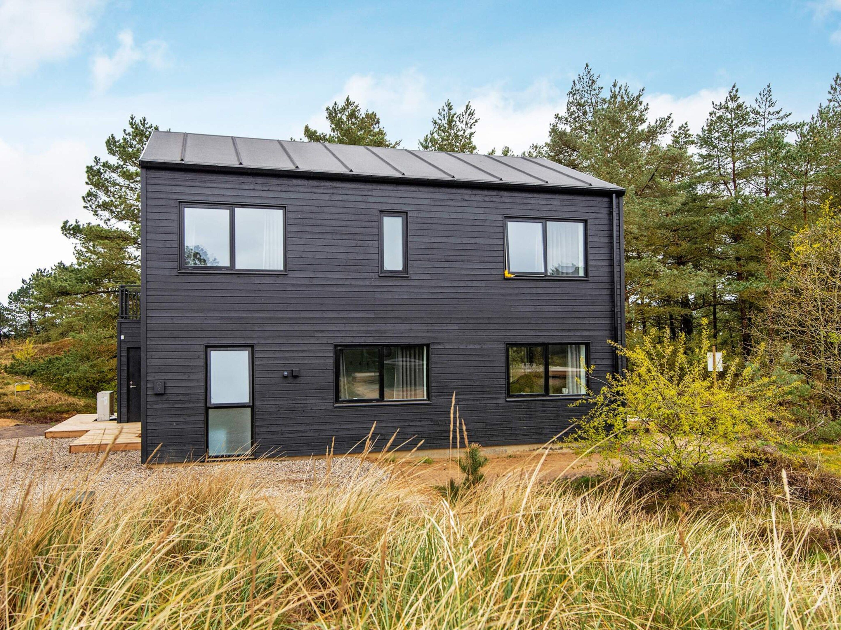 A modern two-story building with a dark exterior, large windows, and a flat roof.
