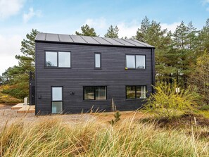 Un bâtiment moderne à deux étages, doté d’une façade sombre, de nombreuses fenêtres et d’un toit plat.