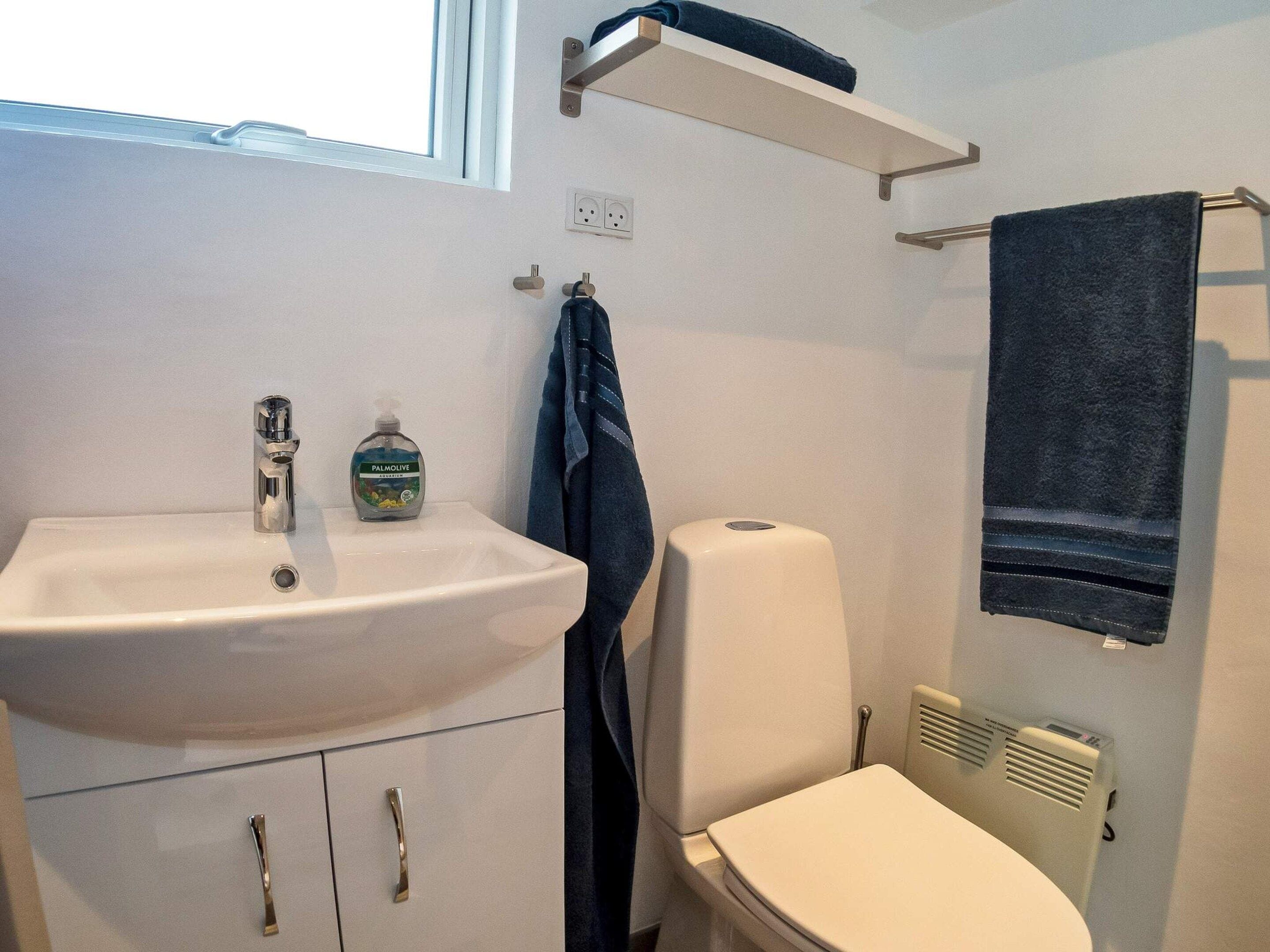 A bathroom with a white sink, a toilet, and a towel rack.