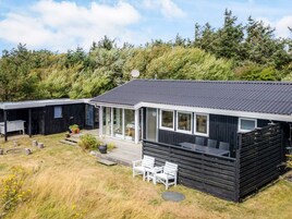 Una cabaña moderna con un amplio balcón y zona de estar exterior.