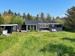 A modern house with a large deck, a covered patio, and a small garden area.