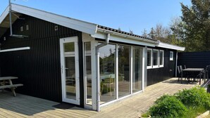 Eine moderne Außenterrasse mit Holzboden, einem Essbereich mit Tisch und Stühlen sowie Kübelpflanzen.