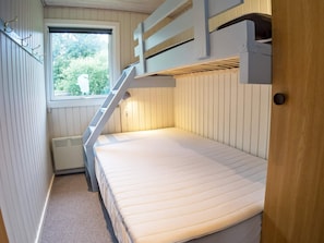 A bunk bed room with a window, a radiator, and a door.