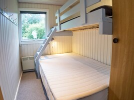 Dormitorio con literas, ventana, radiador y puerta.