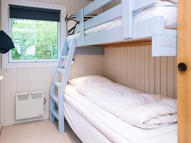 Dormitorio con literas, ventana y radiador blanco.