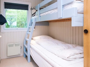 A bunk bed room with a window, a ladder, and a white radiator.