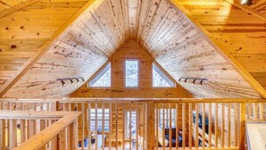 A wooden attic room with a sloped ceiling, skylights, and a wooden railing.