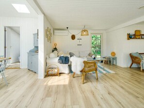 Relax in this serene living area with a high ceiling, featuring a sofa, wicker chair, and natural views.