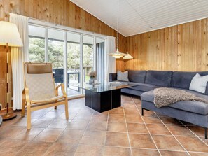 Una sala moderna con una mesa de centro de vidrio, un sofá y una silla de madera.