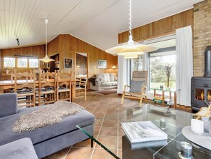 A modern living room with a fireplace, wooden walls, and a dining area.