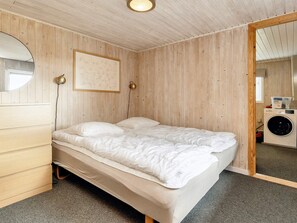 Une chambre à coucher avec un lit, un miroir fixé au mur et un lave-linge.