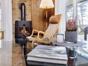 Un ambiente acogedor con chimenea, un sillón, una mesa con un libro y una vela.