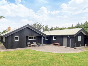 Un bâtiment en bois noir à deux étages, doté d’un toit en pente, d’un patio couvert avec des sièges extérieurs et d’une enseigne portant le numéro « 30 ».