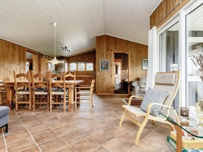 Une pièce spacieuse comprenant un coin repas, un espace salon avec des murs en verre et une vue sur l’extérieur.