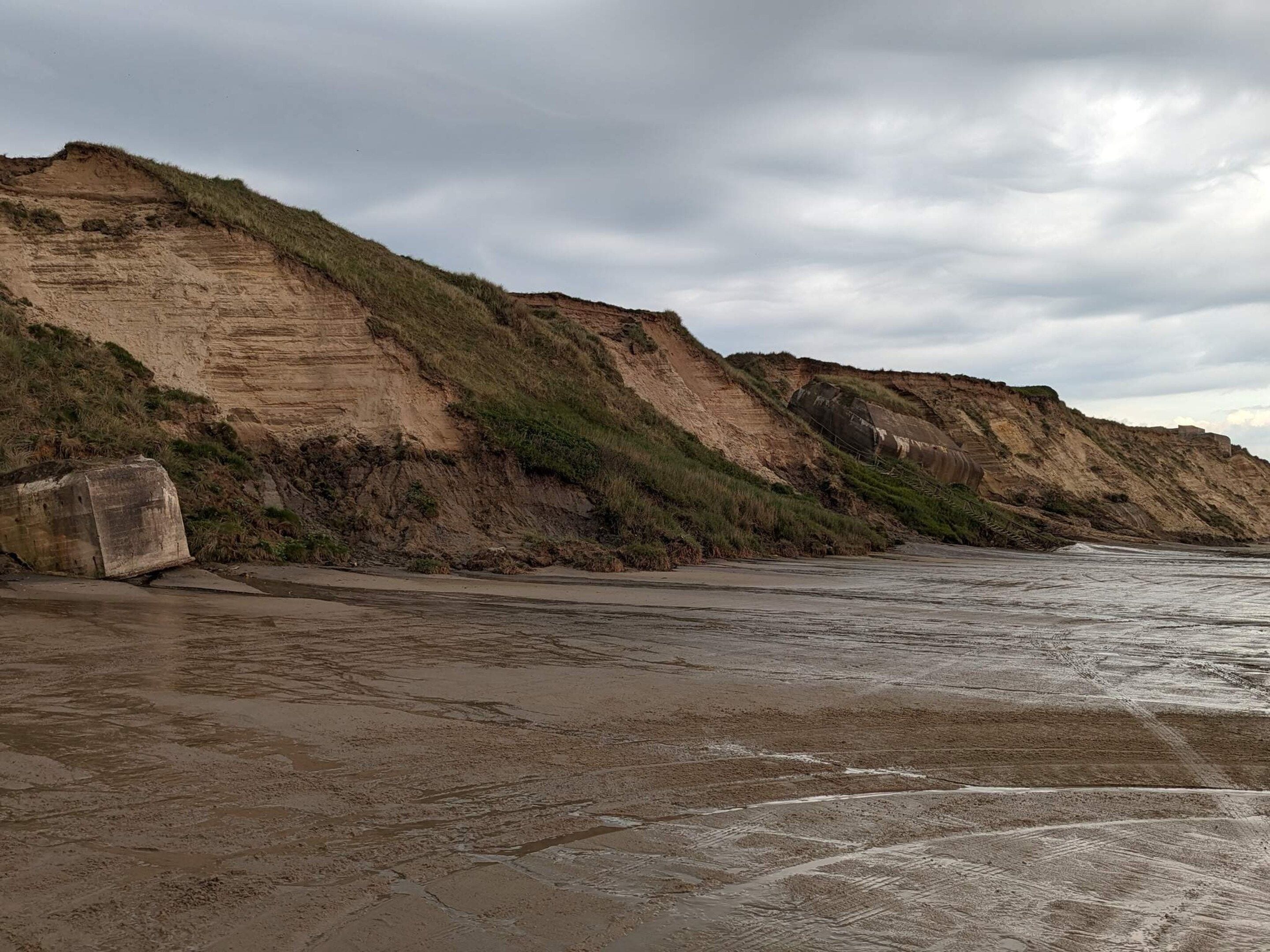 A coastal landscape with cliffs and a sandy beach.
