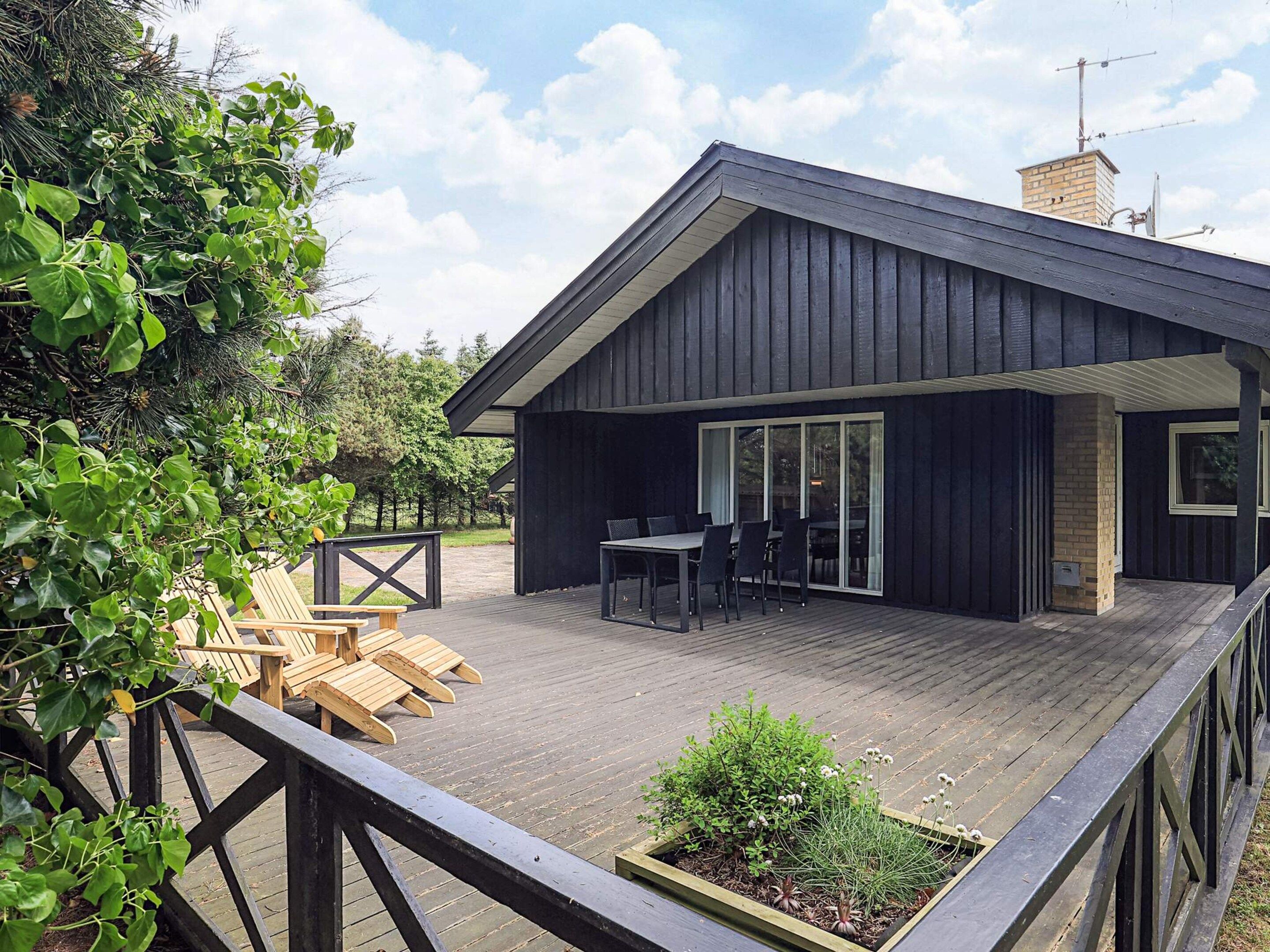 A modern house with a deck, a dining area, and a garden.