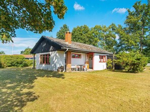 A single-story house with a brick chimney, white walls, and red-framed windows. - 4 Person Holiday Home in Grenaa (Grenaa)