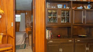 A wooden-paneled room with a bed, a bookshelf, and a cabinet with glass doors.