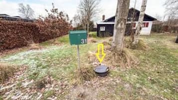 A mailbox with a number 31 sign, a tree, and a small building in the background.