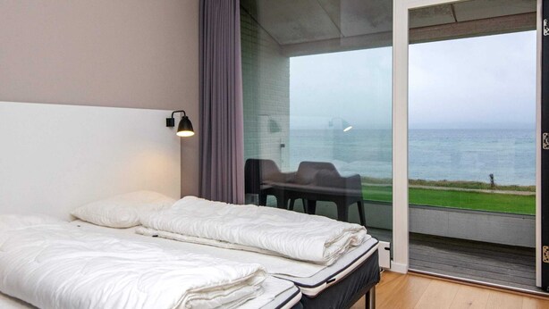 Ein Hotelzimmer mit zwei Betten, Meerblick und einem Balkon mit Stühlen.