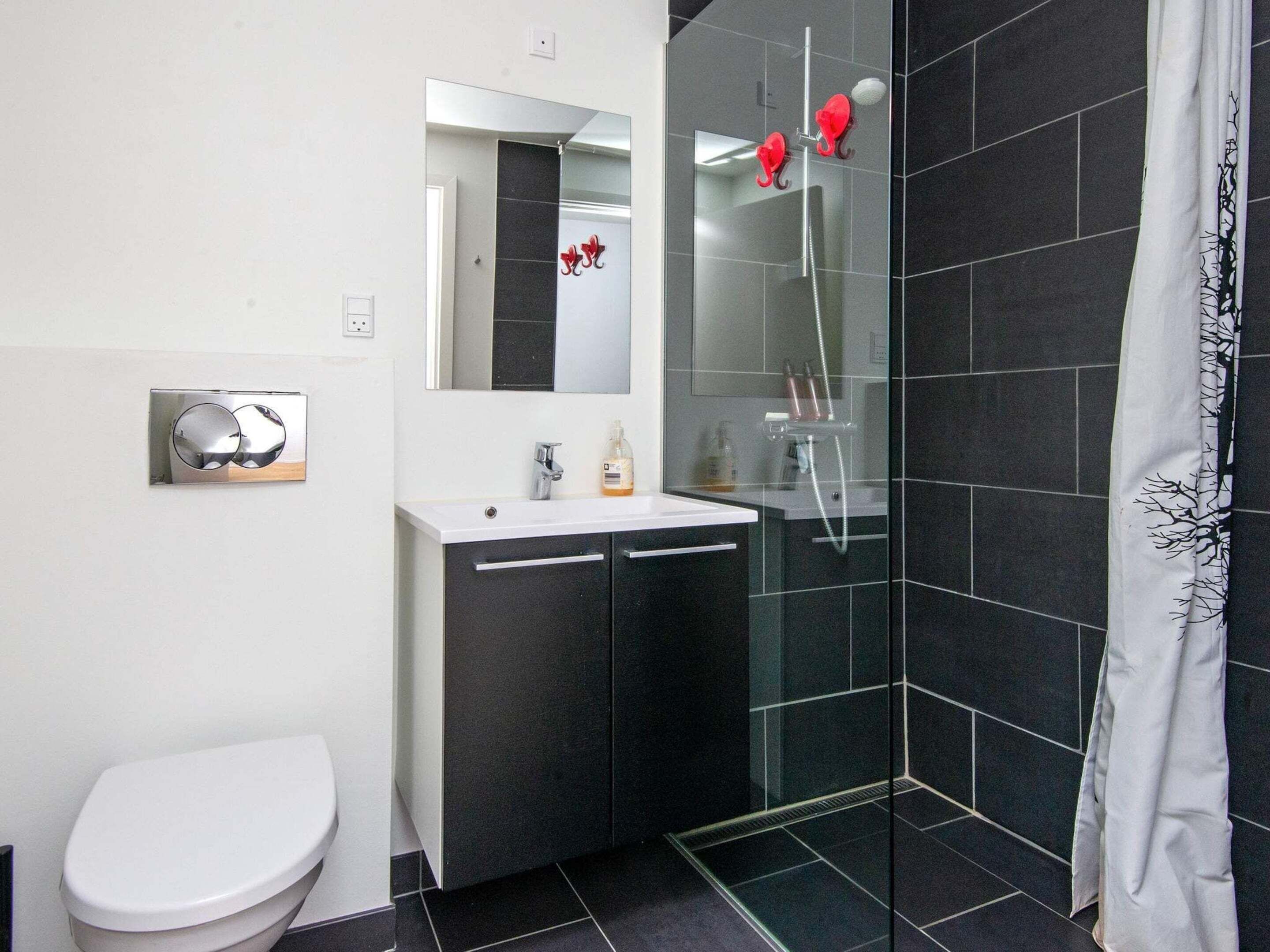 A modern bathroom with a white toilet, a sink with a mirror above, and a glass-enclosed shower area.