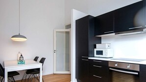 Eine moderne Küche mit schwarzen Schränken, einer weißen Arbeitsplatte, einer Mikrowelle und einem Einbauofen.