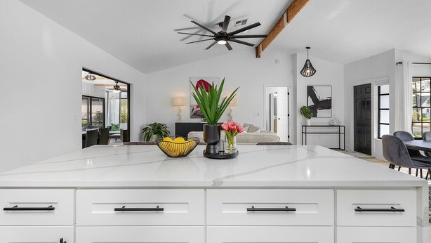 A spacious kitchen with white cabinetry, a central island with decorative items, and a ceiling fan. - Canal View! Walking distance to Marina Village Fully Renovated (Cape Coral)