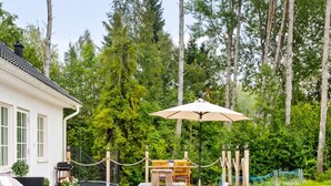 A wooden deck with outdoor furniture, a pergola, and a view of a forested area. - 4 Star Holiday Home in Norrtalje (Norrtälje)