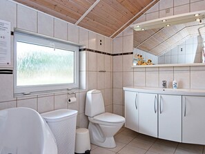 A modern bathroom with a toilet, sink, and window. - 8 Person Holiday Home in Oksbol (Oksbol)