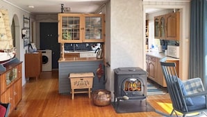 Een gezellige woonkamer met een open haard, houten kastjes en een schommelstoel.