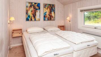 A room with two beds, wooden walls, and two abstract paintings.