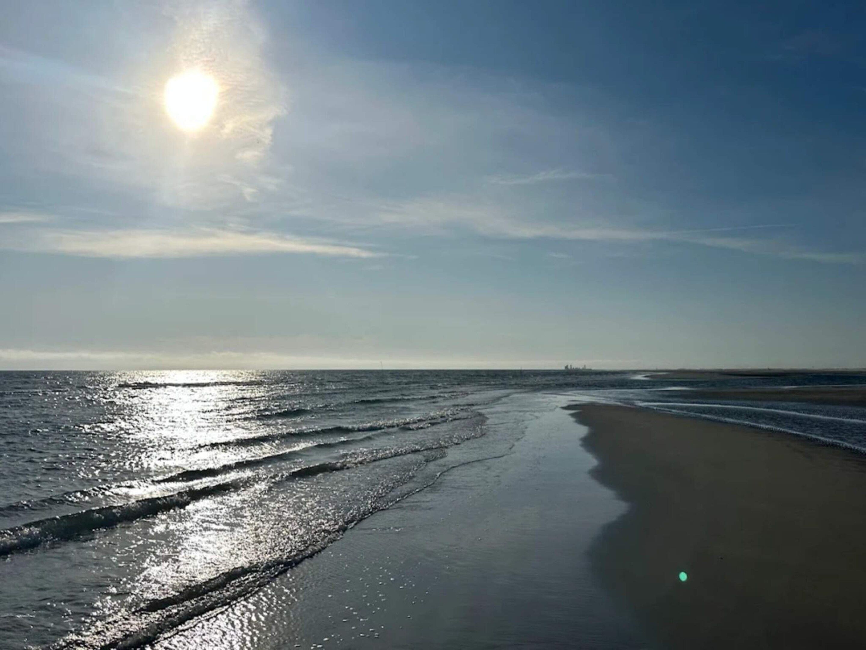 A beach with a clear sky and the sun shining.