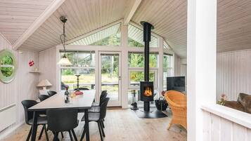 A cozy room with a dining table, chairs, a fireplace, and large windows.