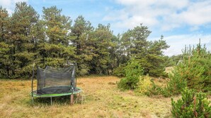 Un trampolí en un camp de gespa amb arbres al fons.