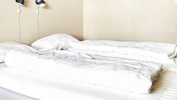 A bed with white bedding and two wall-mounted earphones.