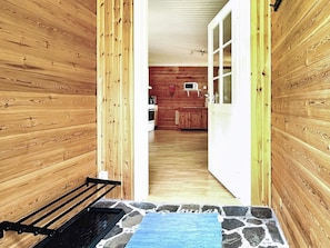 Un interior de madera con cocina, un banco y suelo de baldosas de piedra.