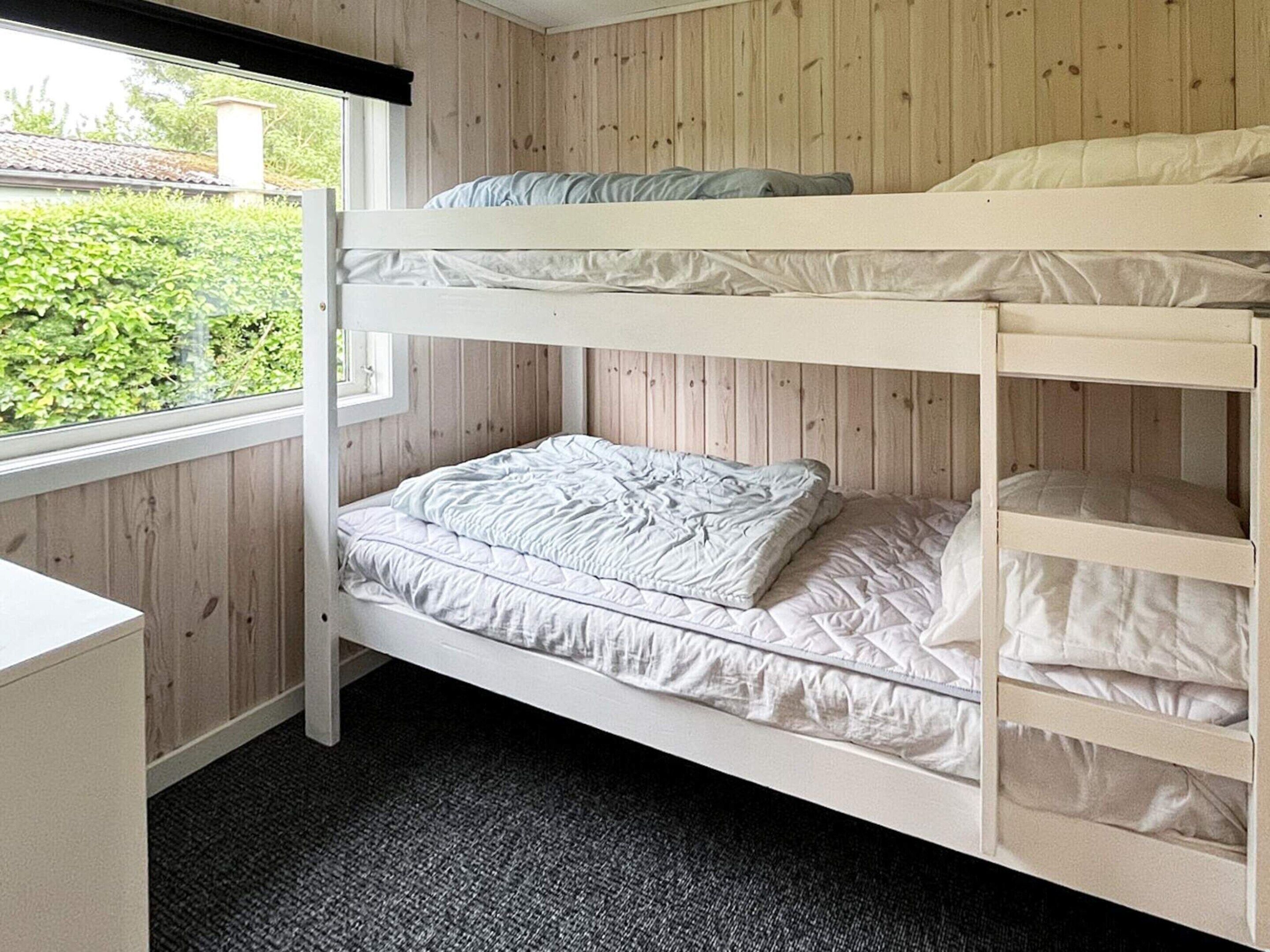 Quarto com beliche, escrivaninha e piso coberto por carpete.