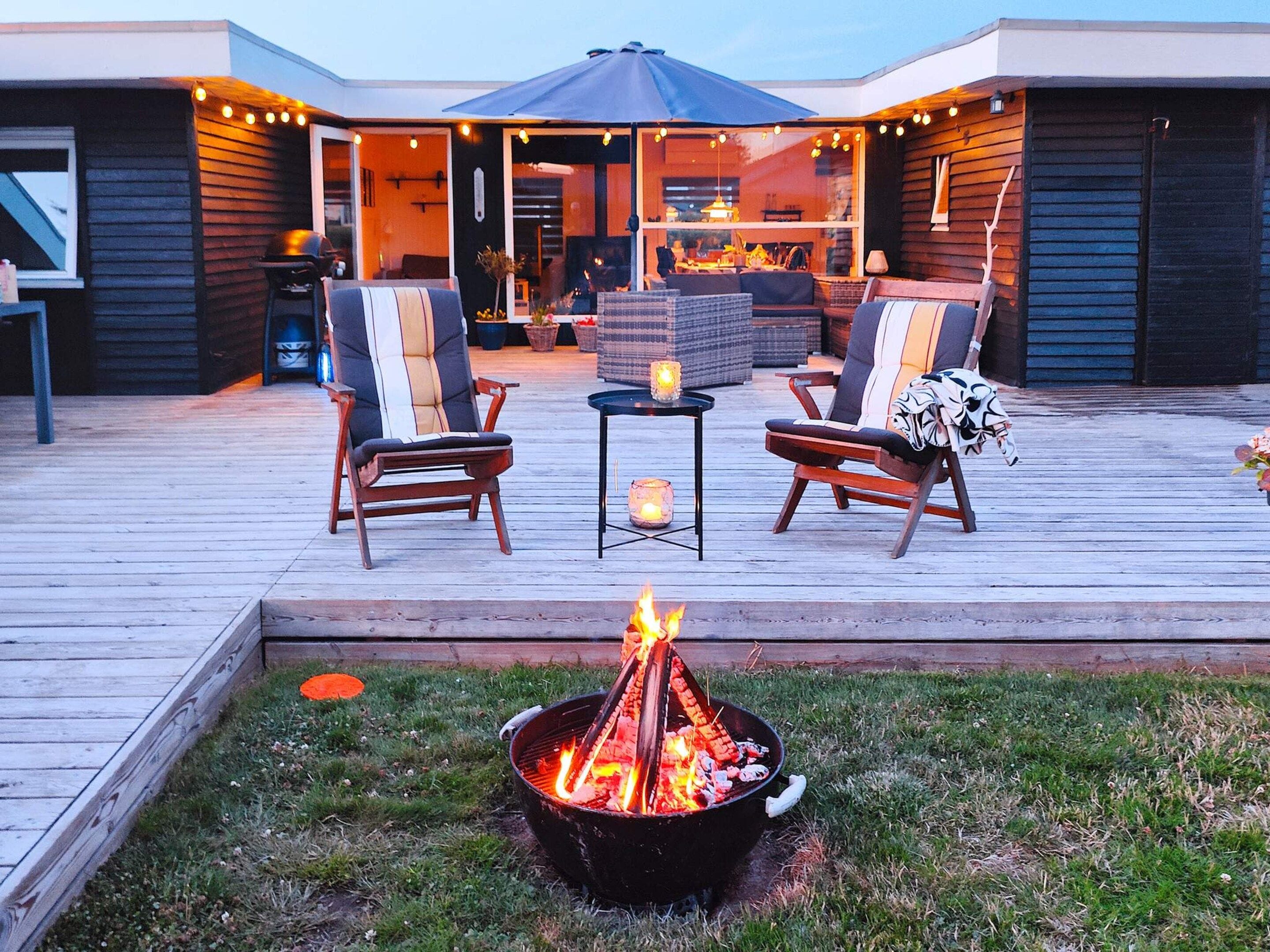 An outdoor deck with a fire pit, two chairs, and a table with candles.