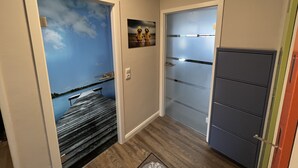 Un pasillo con piso de madera, una puerta con un mural del cielo azul, una pequeña imagen en la pared y un armario azul.